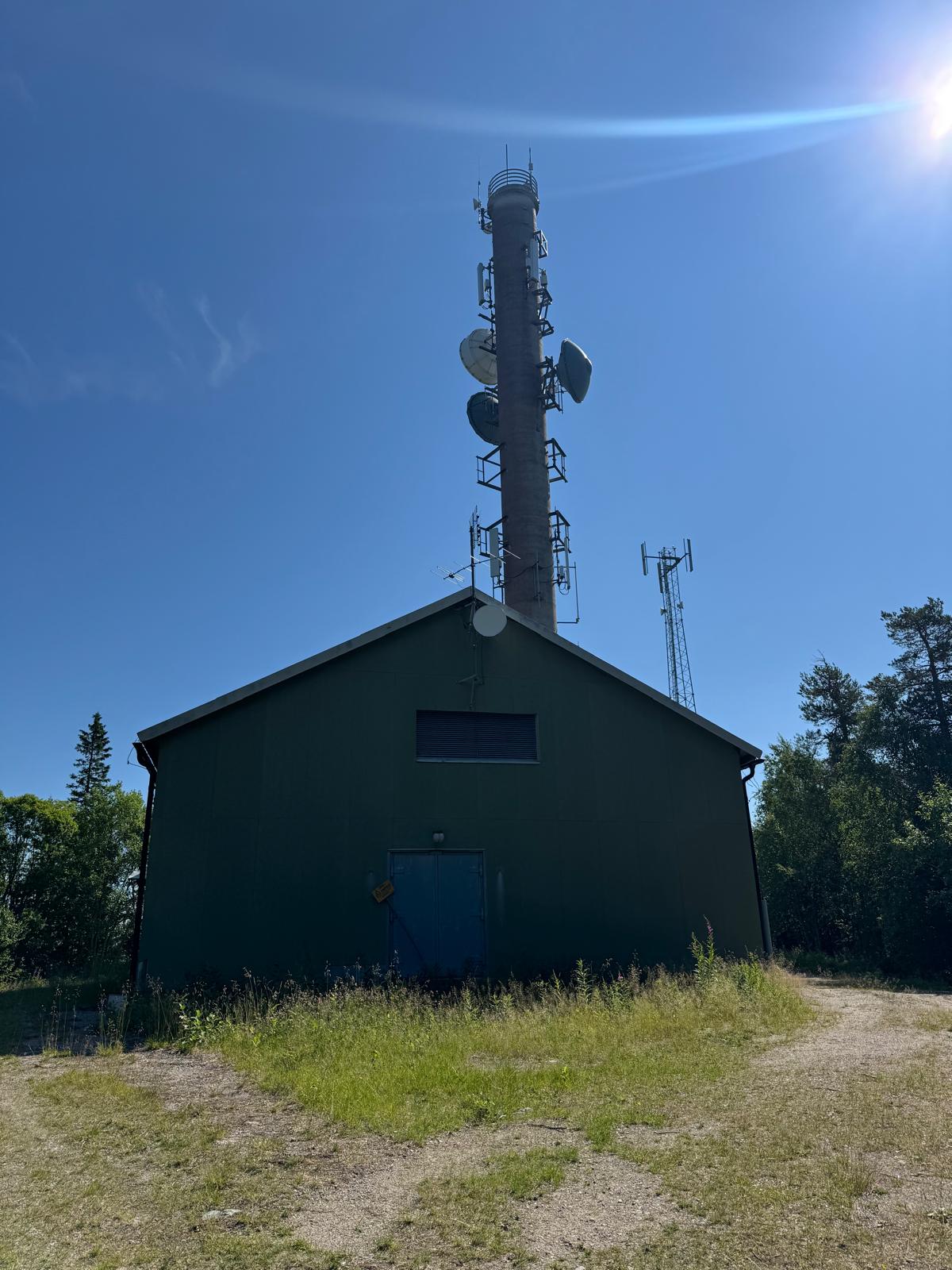 The green relay building beneath the concrete mast