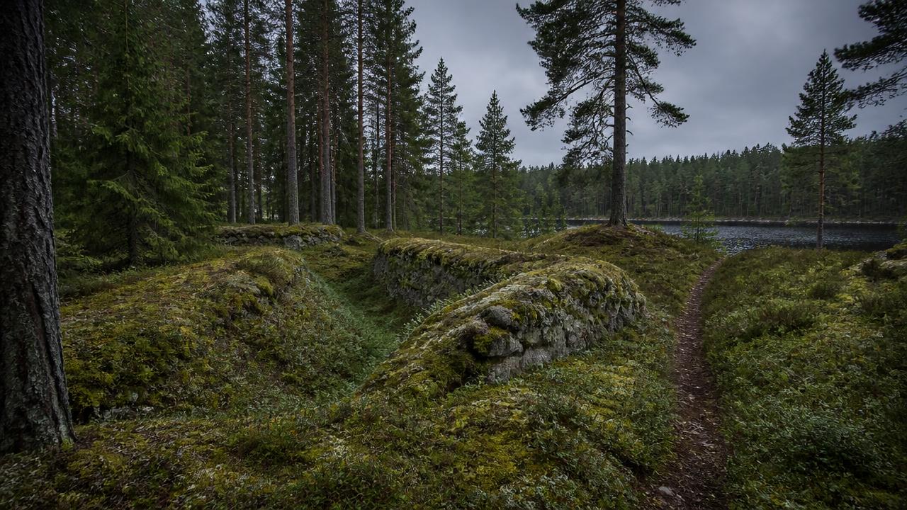 Overgrown stone and earth ramparts of Gransjö skans beside a forest lake