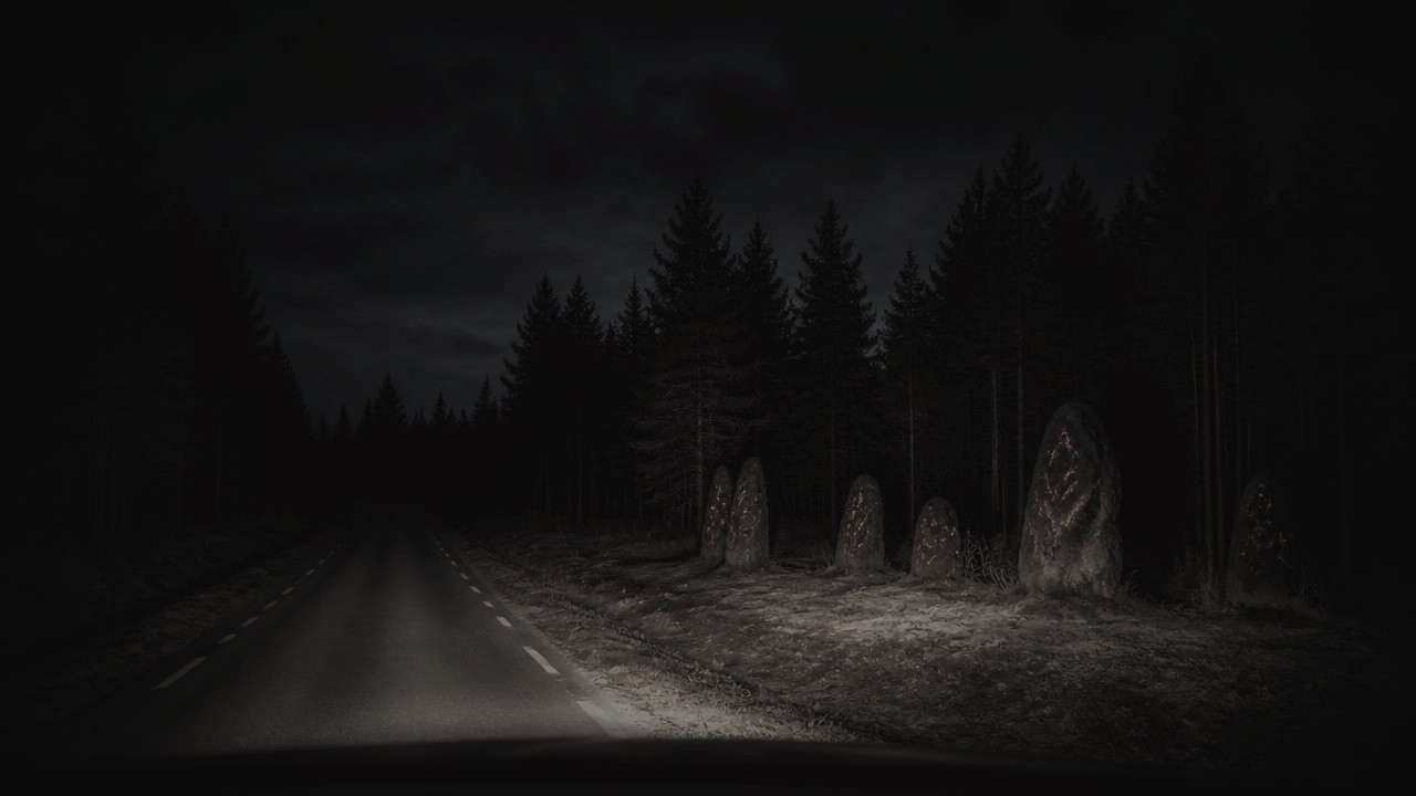 A dark forest road at night with glowing scorched stones beside the asphalt
