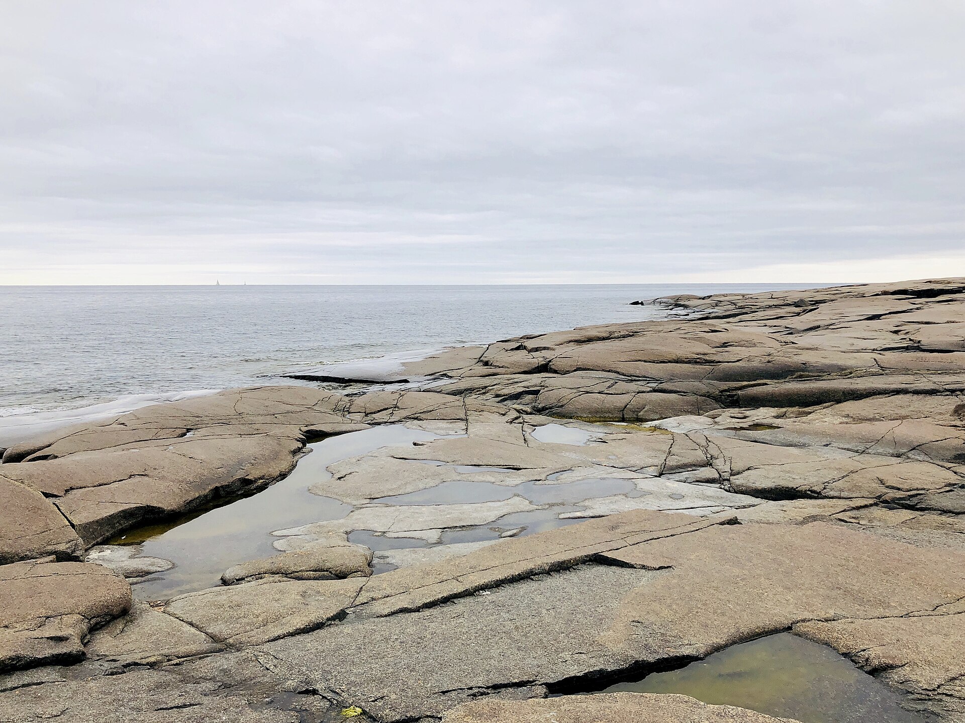 Deep circular potholes in polished diabase rock along the Rotsidan coastline at dusk